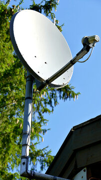 White Satellite Dish Mounted on Roof Against Clear Blue Sky
