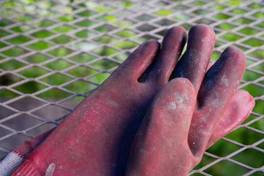 Well-worn red rubber gloves for farm work