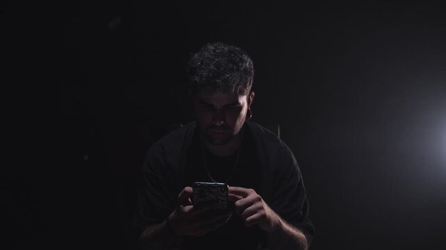 Man Scrolling Smartphone Alone in Dark Room
