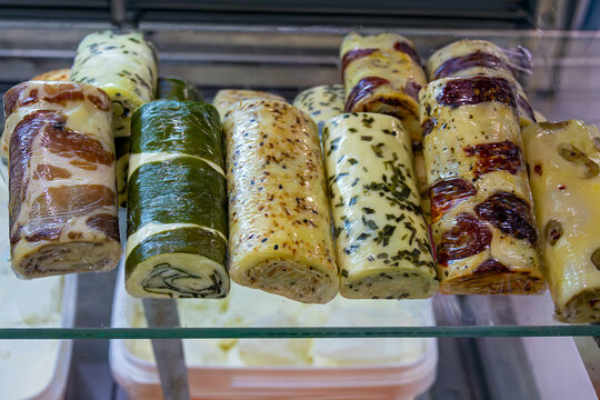 Traditional cheese rolls with ham and herb spices on a shelf sold on market stall