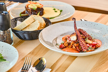 Grilled octopus dish served on a plate with vegetables and bread © Elizaveta