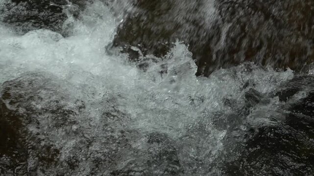 Slow Motion Close Up of Clear Water Splashing Over Rocks