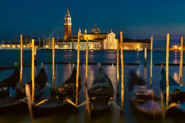 Gondolas Moored at San Marco Pier at Night with San Giorgio Maggiore Church Illuminated in Venice, Italy © DannyIacob