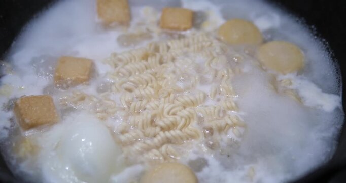 Close up of boiling instant noodles with fish tofu in hot soup pot