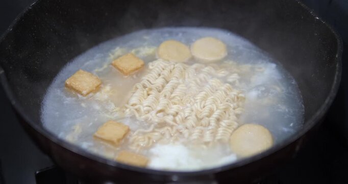 Close up of boiling instant noodles with fish tofu in hot soup pot