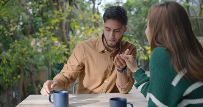 African American couple on patio holding hands, man letting go reaching for blue mug while bonding