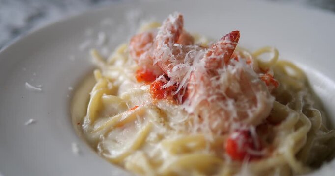 Close up of creamy fettuccine Alfredo pasta with shrimp and grated parmesan cheese