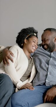 Vertical video: African couple sharing soft chat and mutual gaze on sofa at home, showing affection
