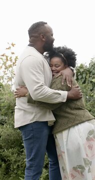 Vertical video: African American couple embracing at park man with watch woman with headband loving