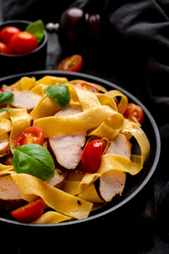 Premium pasta with roasted chicken pieces for savory meal. Creative cooking and gourmet lifestyle. Close perspective of rich delicious dinner flavors captured against deep dark background.