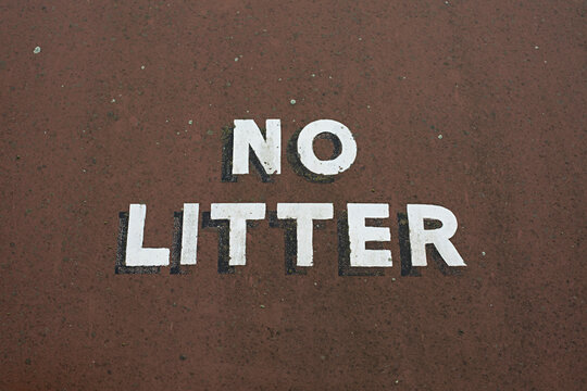 No Litter sign hand painted on weathered brown background