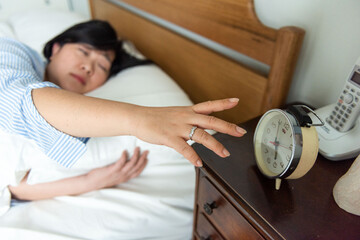 Woman reaching alarm clock sleepily
