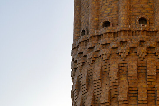 Architectural detail showing carved brick patterns and small windows on a historic brick tower
