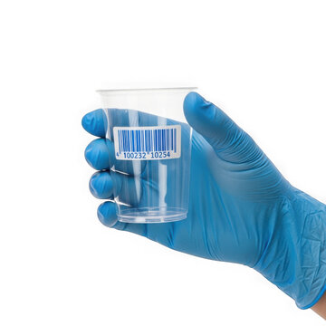 A person wearing blue nitrile gloves holding a small clear plastic medical testing cup for laboratory or clinical analysis isolated on transparent background