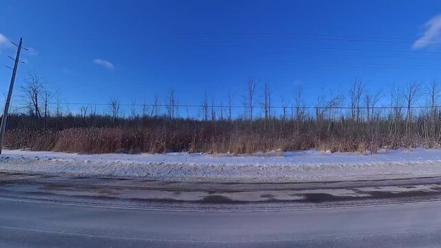 Point of view of car side view driving plate in Innisfil town in Ontario, Canada high way. Travelling in February winter snowy road. Travel and destination to lake Simcoe for Ice fishing.