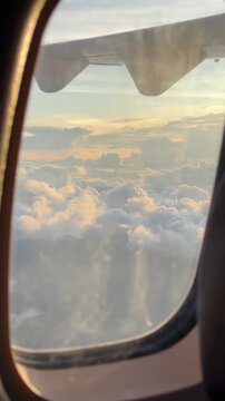Aerial video view through airplane window looking out at clouds and wing during sunset flight
