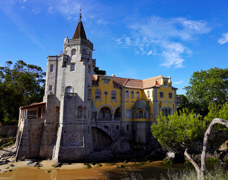 The Pal&aacute;cio dos Condes de Castro Guimar&atilde;es, a romantic revivalist palace featuring a prominent stone tower and pointed spire, sits along the coastal inlet in Cascais, Portugal