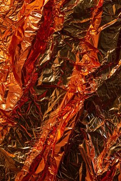 Abstract background of crumpled copper foil with a warm metallic sheen, showcasing intricate folds and reflective surfaces