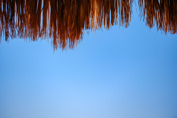 Straw parasol roof against clear blue sky in sunny weather © Buğra Kaan Ersoy