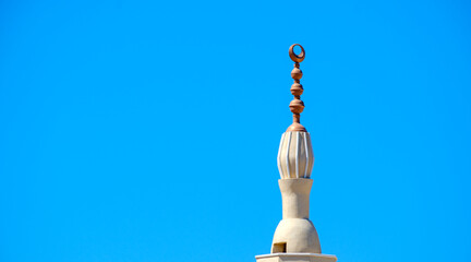 Pinnacle of a minaret with islamic crescent symbol against blue sky © Bugra Kaan Ersoy