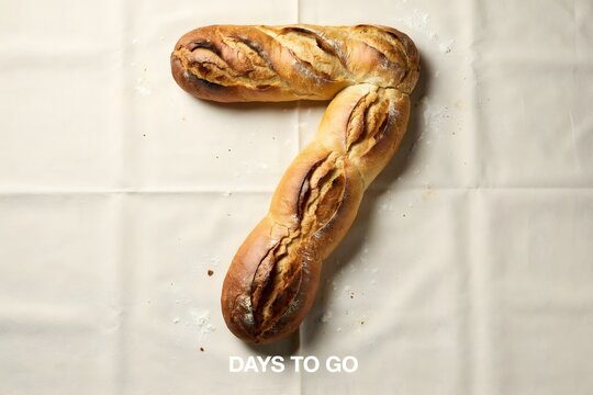 Number seven shaped fresh crusty baguette bread loaf on a rustic white bakery background