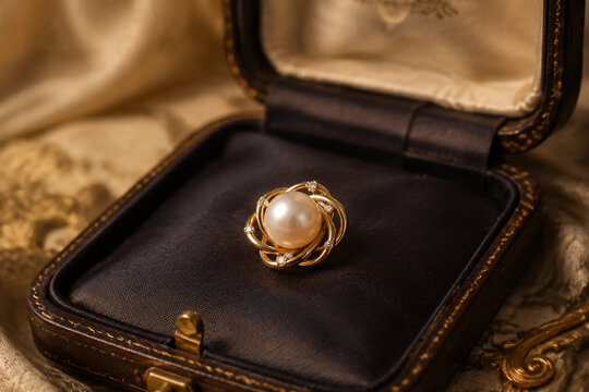 Pearl brooch resting on dark silk lining inside an antique jewelry box.