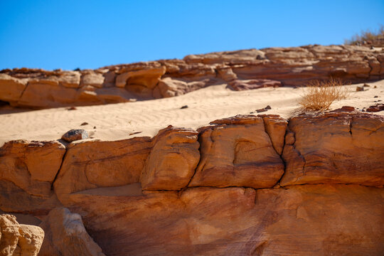 Layered desert cliff edge under a clear blue sky in an arid landscape