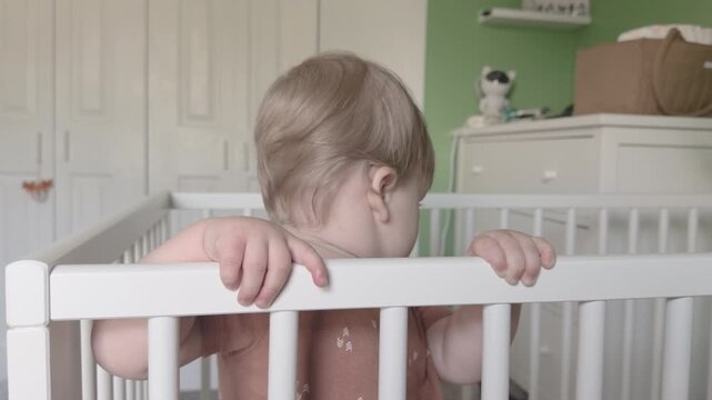 Young toddler standing in crib looking at camera 4k
