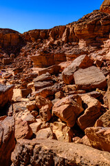 Rugged desert terrain with weathered sandstone rock formations and boulders under bright sunlight © Buğra Kaan Ersoy
