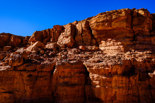 Rugged desert canyon cliffside showing stratified geological layers under bright daylight