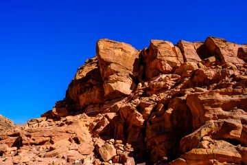 Fototapete Braun Dramatic desert rock outcrop against a vivid blue sky in an arid landscape  © Buğra Kaan Ersoy
