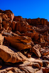 Dramatic sandstone boulders and steep rocky cliff face in an arid desert canyon © Buğra Kaan Ersoy