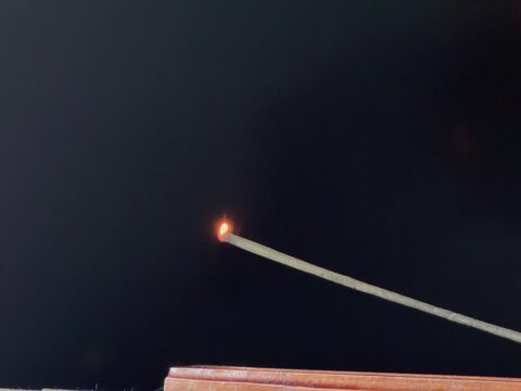 Lit aromatic incense stick releasing pleasantly scented smoke, in a wooden holder. Aromatherapy, meditation, relaxation, spirituality, and yoga concept, with a calming atmosphere.
