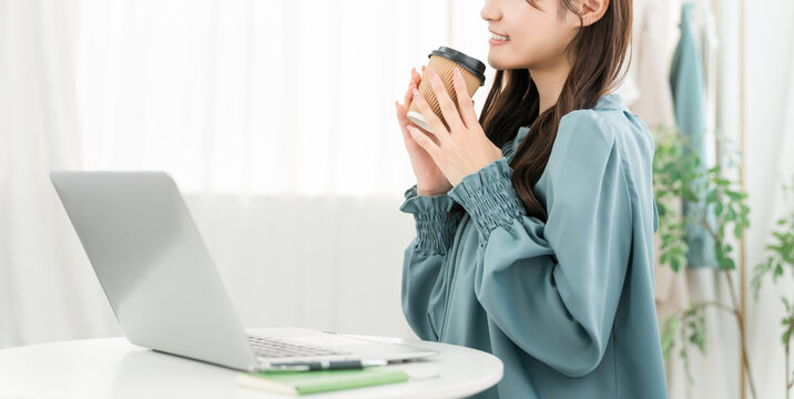 A young Asian businesswoman drinking coffee in her office/workplace.