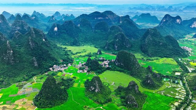 Aerial view of karst valley with green rice fields and a rural village surrounded by mountains in Guilin, China