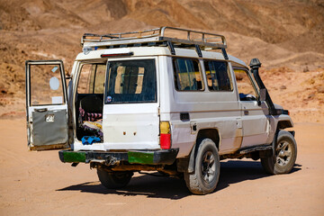 Rear view of a white off road safari vehicle parked on desert sand © Buğra Kaan Ersoy