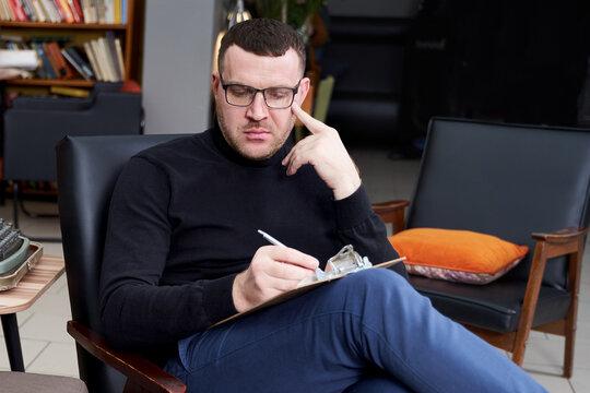 Therapist writing down notes during therapy sitting in a chair
