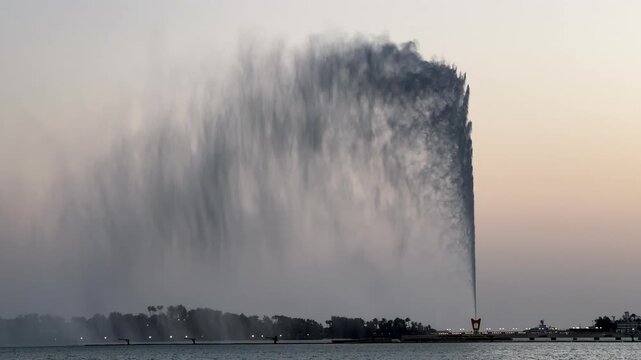 Close-up shot of King Fahd Fountain water jet shooting upward with soft mist against a twilight sky in Jeddah.