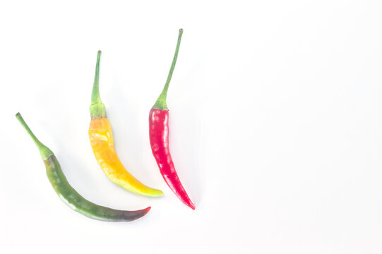 Green, yellow and red fresh chili peppers on white background, top view with copy space