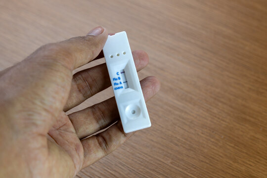 Hand holding a positive Influenza A rapid antigen test cassette. Viral infection, seasonal illness, and at-home medical care concept.