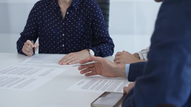 Corporate professionals analyzing contract details, gesturing toward key points while negotiating partnership terms in modern office boardroom
