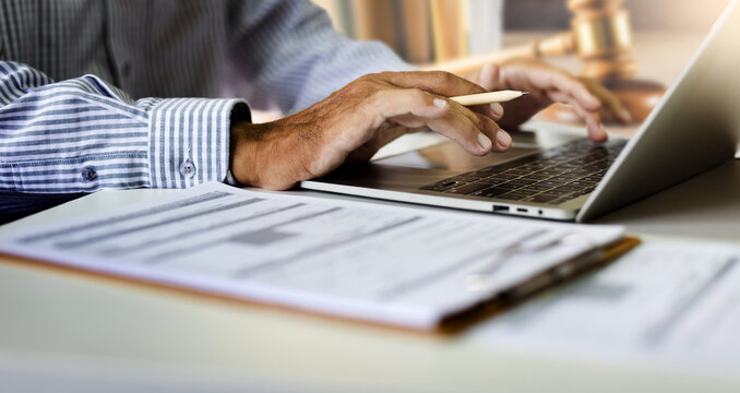 close up shot, asian businessman using laptop working on desk. legal expert, professional lawyer reading and checking financial document and business contract