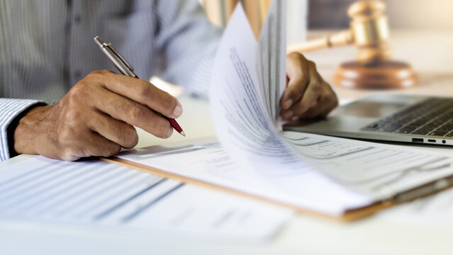 close up shot, asian businessman working on desk reading document contract. legal expert, professional lawyer reading and checking financial document business contract