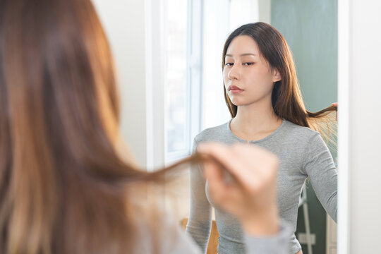 Hair problem person. Serious, worried asian young woman, girl hand holding damaged ends of hair, heat damage and dry hair, split ends and hair texture thinning, healthcare of beauty people concept.