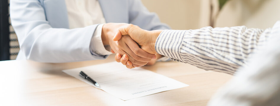 Close up successful job interview and recruitment concept with professional HR manager shaking hands with a selected candidate after a positive career hiring agreement in a bright modern office.