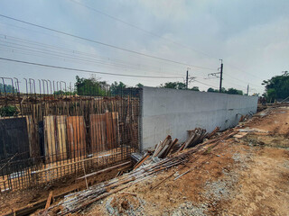 Concrete retaining wall construction site with exposed rebar reinforcement. © Hengki Tj