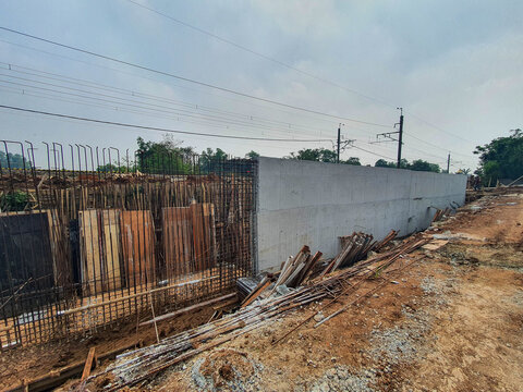 Concrete retaining wall construction site with exposed rebar reinforcement.