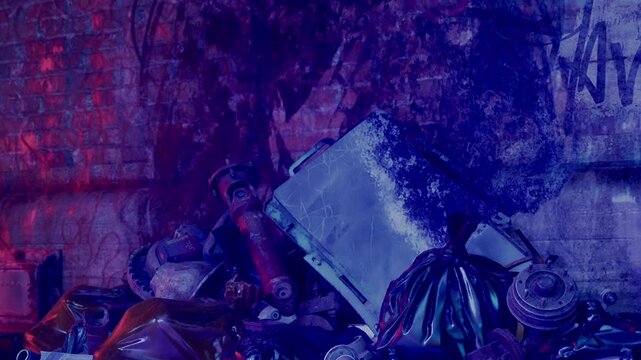 A pile of trash and discarded items is seen in a dimly lit area. Various pieces of junk are scattered across the ground near a brick wall. The setting shows the effects of neglect.