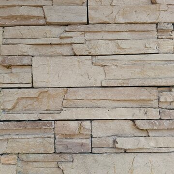 Modern beige stacked stone wall tiles texture background, seamless decorative stone cladding close up