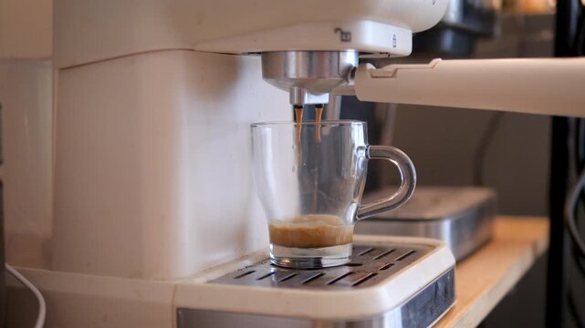 Close-up view of an espresso machine extracting fresh coffee into a glass cup, the brewing process and crema forming during preparation